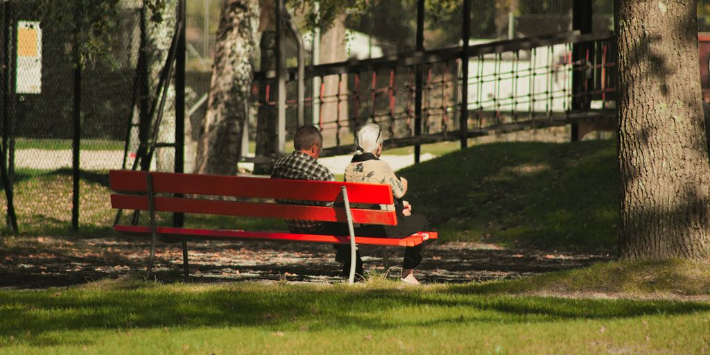 a man sitting on a red bench in a park