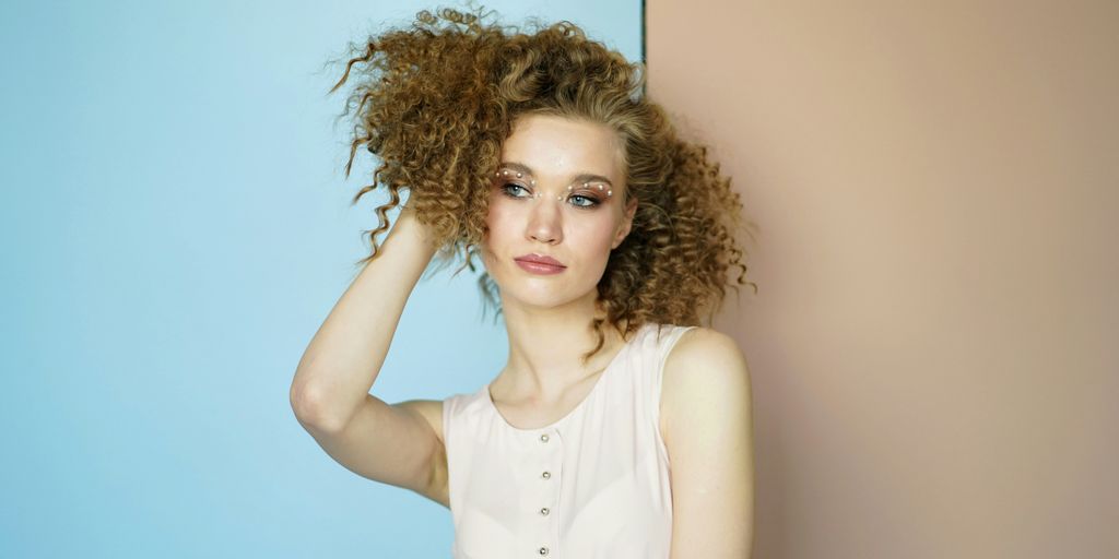 woman leaning on wall holding her hair