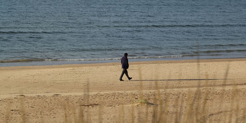person walking near beach line