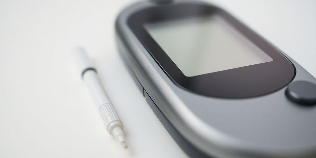 Close-up of a digital glucose meter and lancet device.