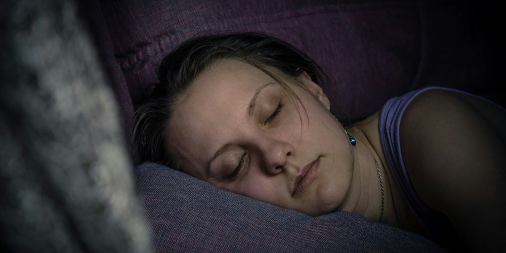 a woman sleeping on a couch with her eyes closed