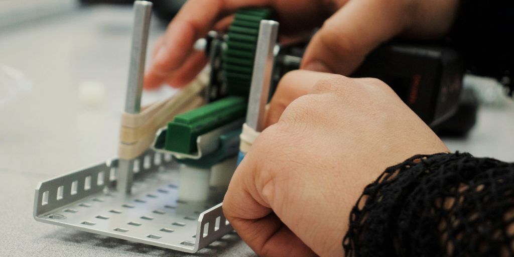 person in black and white long sleeve shirt using white and green braille machine