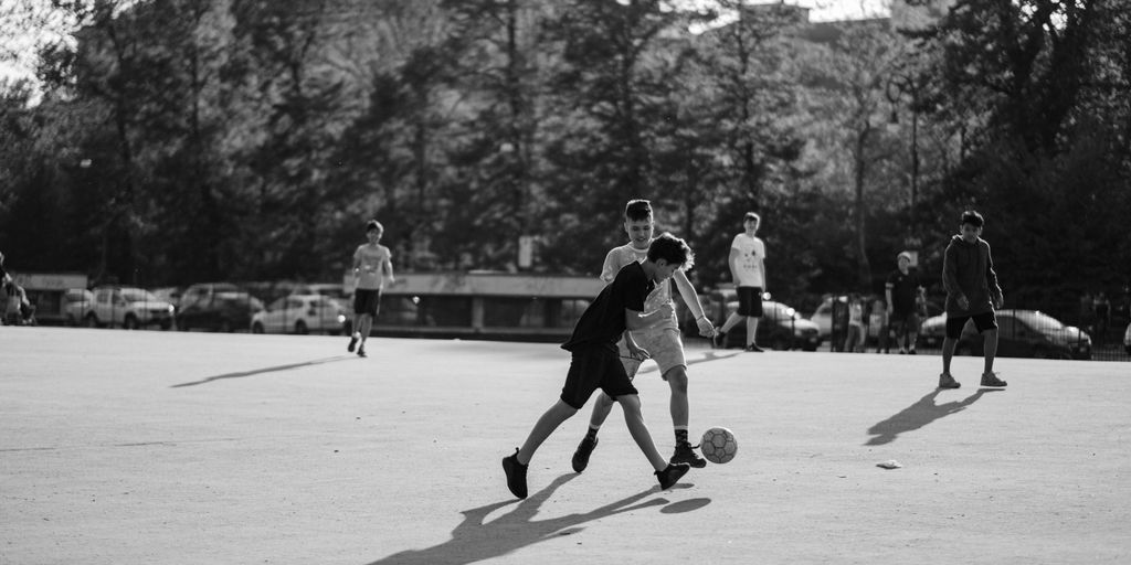 grayscale photo of group of man playing soccer on field