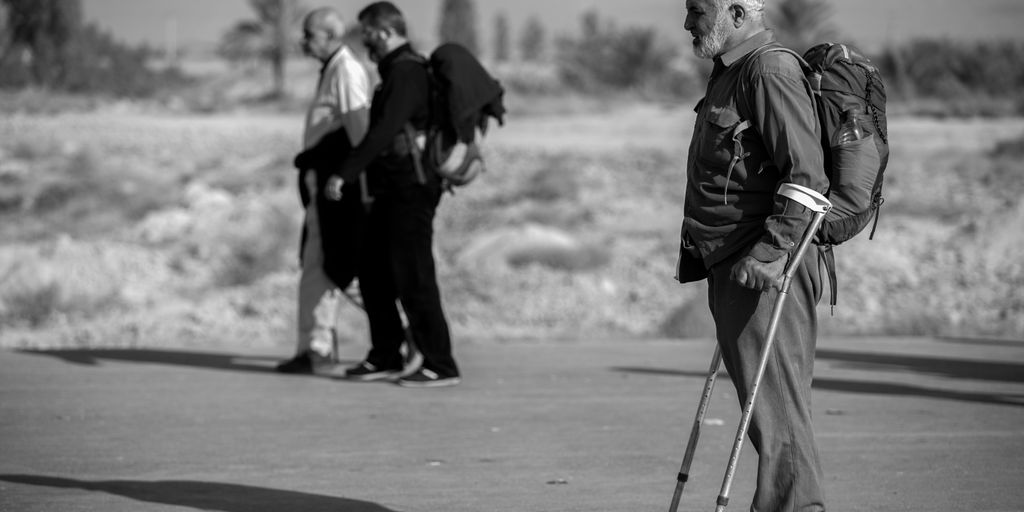 grayscale photo of man with crutches