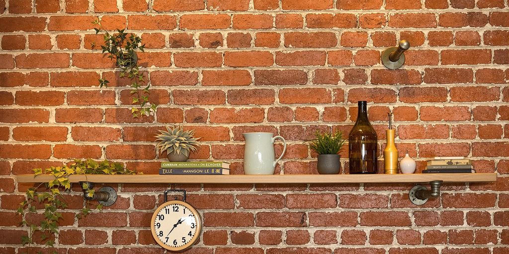 Industrial hanging pipe shelf with plants and decor items.