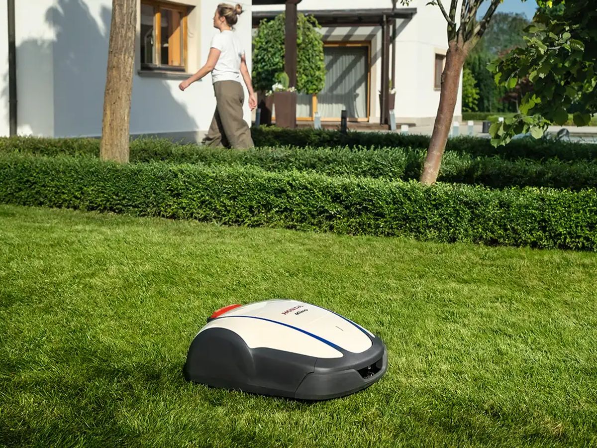 A robotic lawn mower operates in a well-kept garden.