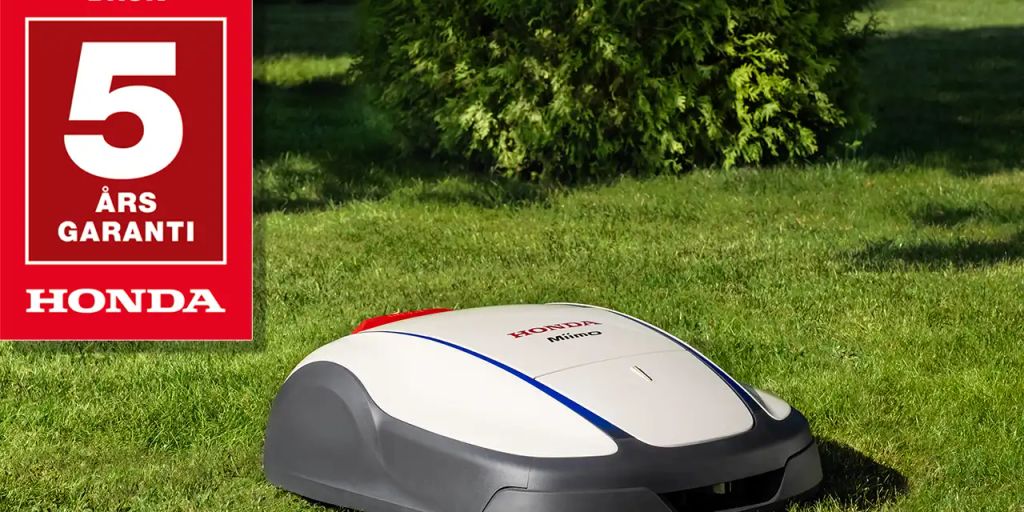 A robotic mower on green grass, featuring a warranty sign.