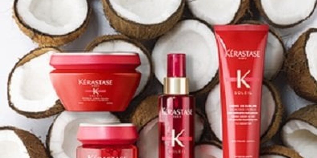 Haircare products displayed among halved coconuts on a white background.
