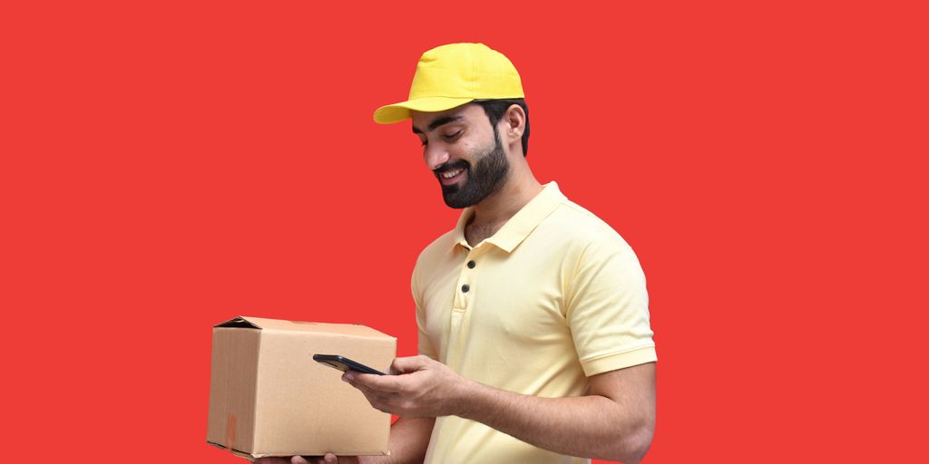 a man in a hard hat holding a phone and a box
