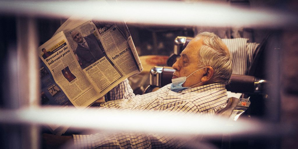 grayscale photo of man reading newspaper