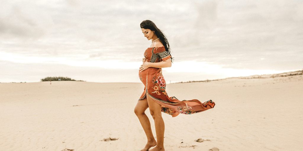 woman holding her womb standing on seashore