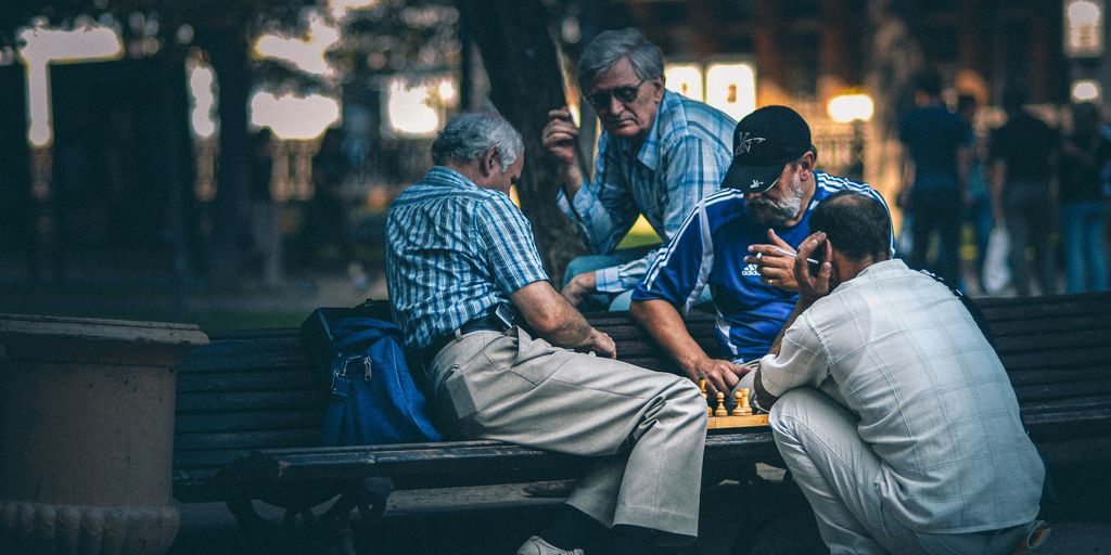 man in blue and white plaid dress shirt sitting on bench