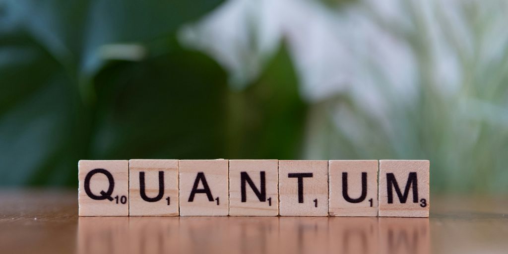 A wooden block spelling the word quanntum on a table