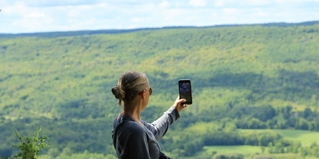 woman in black jacket taking photo of green grass field during daytime