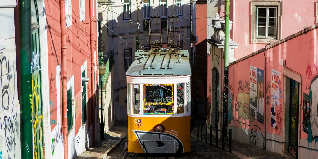 yellow and white tram between pink walls during daytime