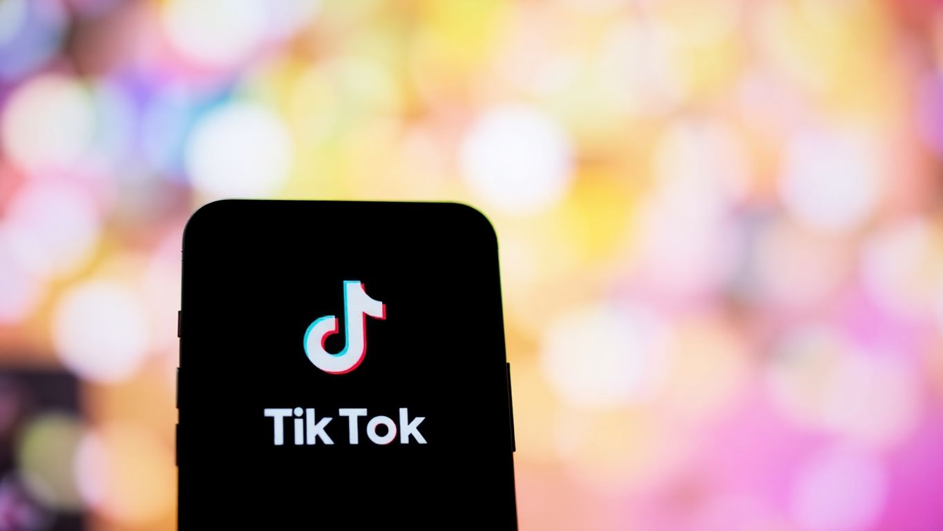 Smartphone with TikTok logo amidst colorful blurred background.