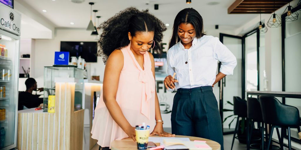 A couple of women standing next to a table