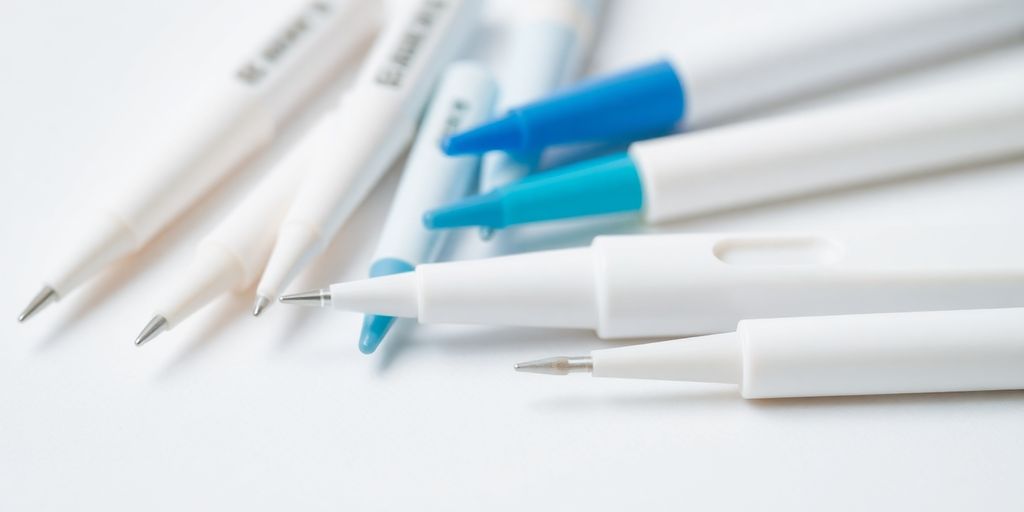 Close-up of various blood sugar testing needles on white.