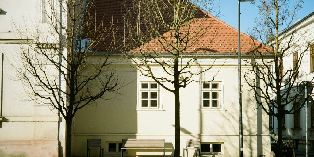 a white building with a red roof and trees in front of it