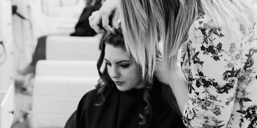 grayscale photography of woman getting her hair done inside salon
