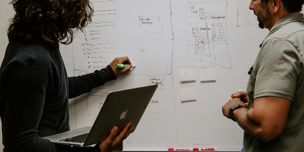 man wearing gray polo shirt beside dry-erase board