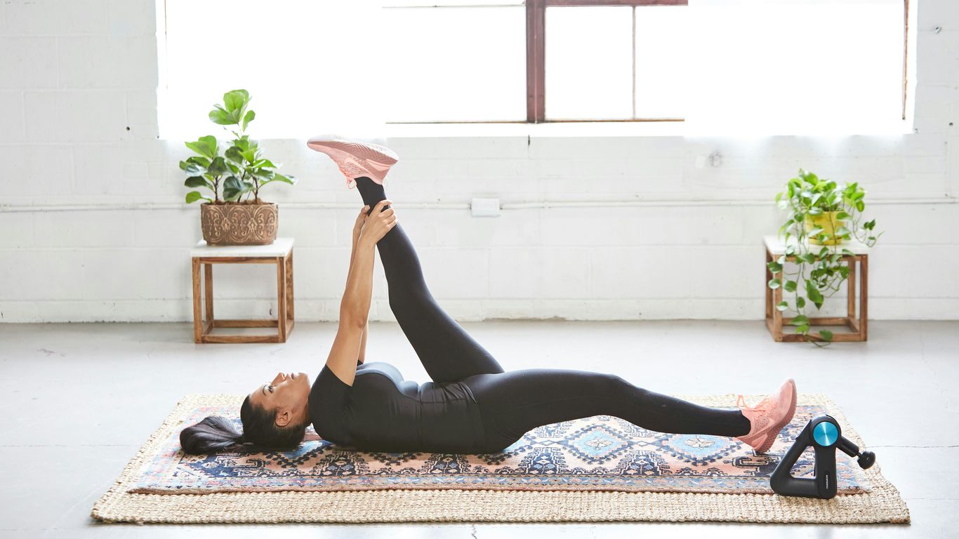 woman in black tank top and black leggings lying on black and white floral area rug