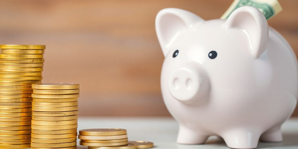 Pièces d'or près d'une tirelire avec des billets.