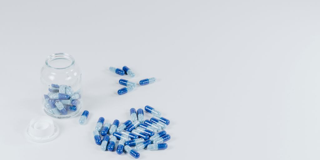 white-and-gray pills beside jar with pills