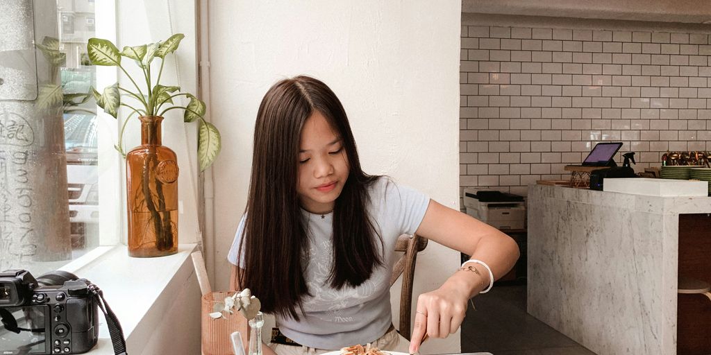 woman in gray shirt sitting on chair in front of table with food