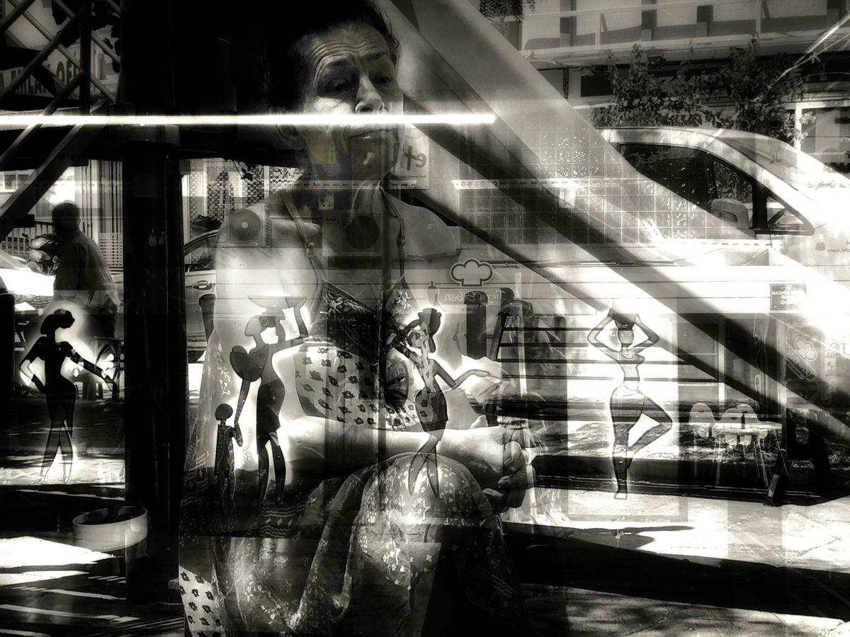 A black and white photo of a man sitting on a bench