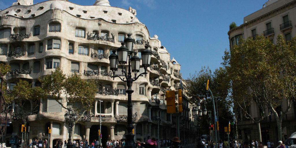 A group of people walking across a street next to tall buildings