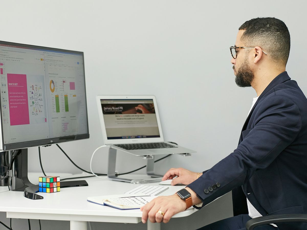 a man sitting at a desk with a laptop and a computer