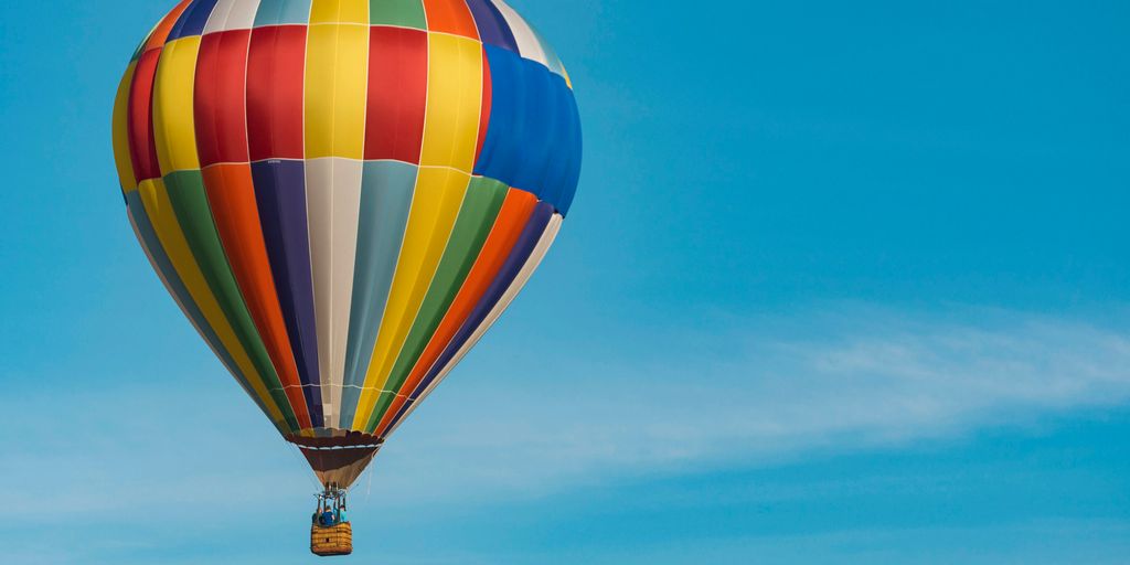 panning photography of flying blue, yellow, and red hot air balloon