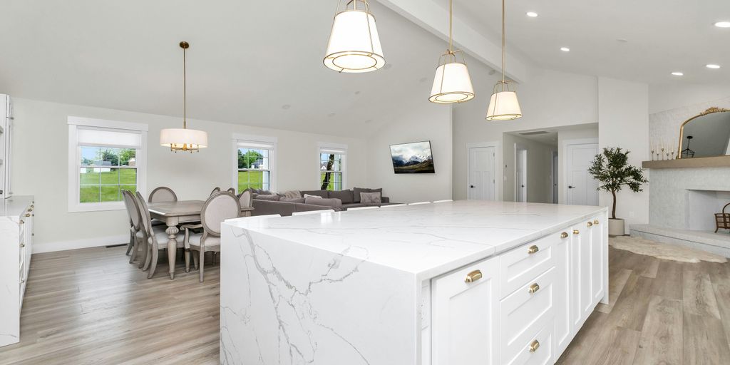 a large white kitchen with a marble island