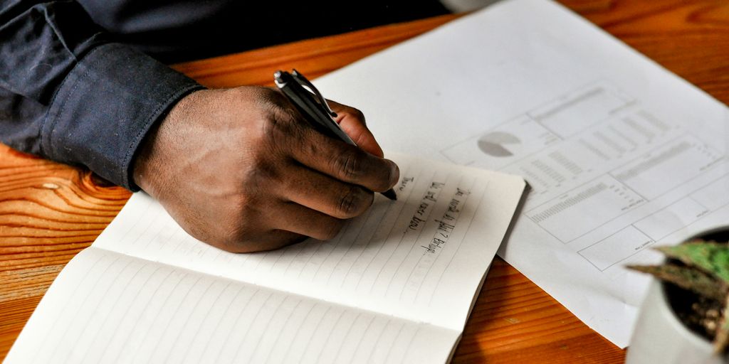 a hand holding a pen over a notebook