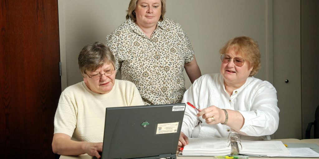 woman in white cardigan sitting beside woman in black and white floral shirt