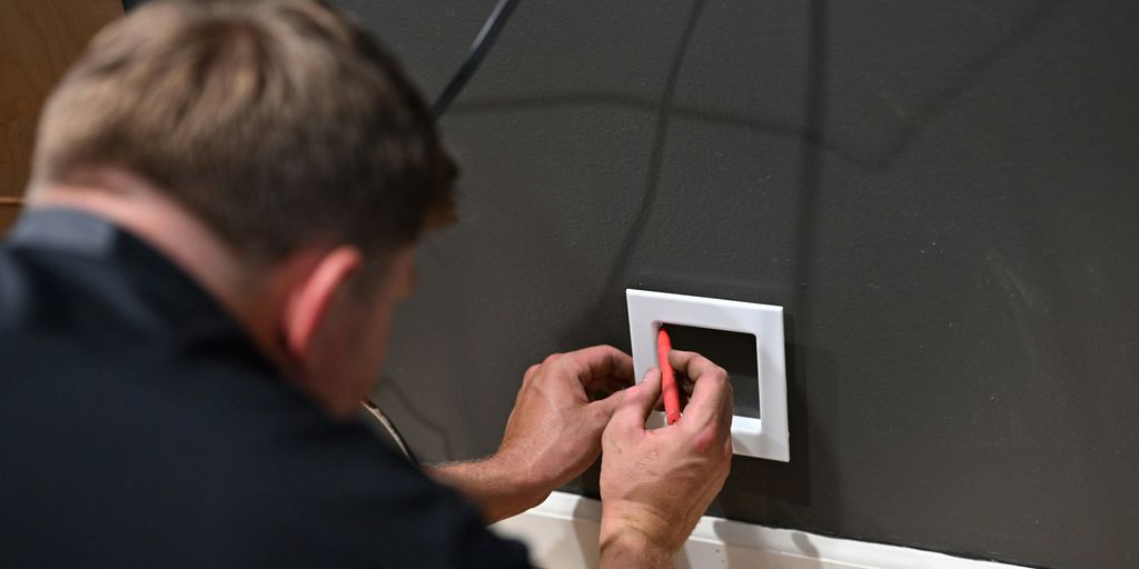 a man fixing a light switch on a wall