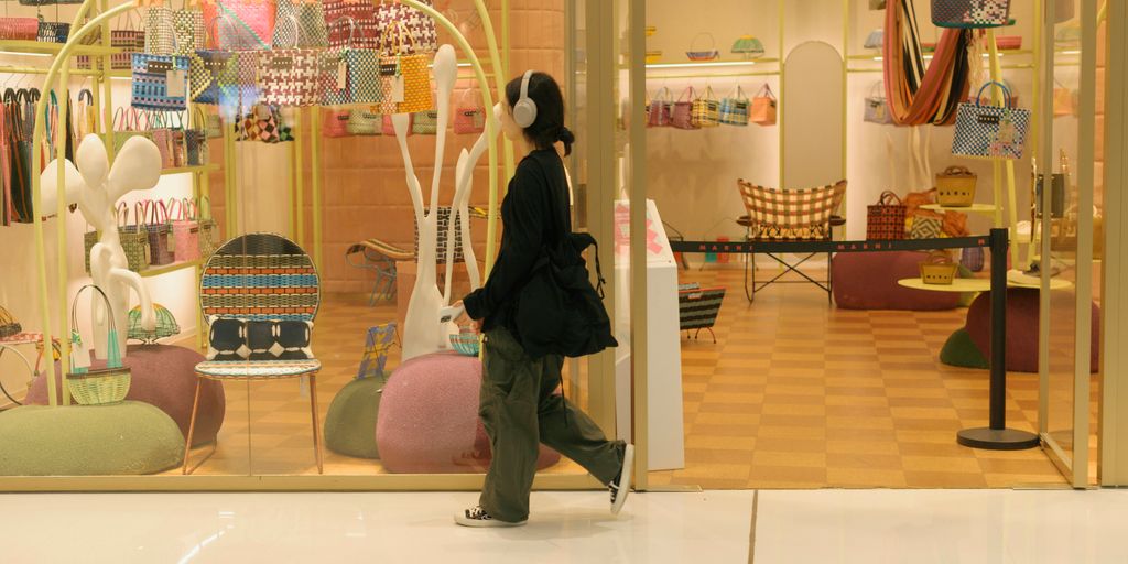 A woman walking past a store front window