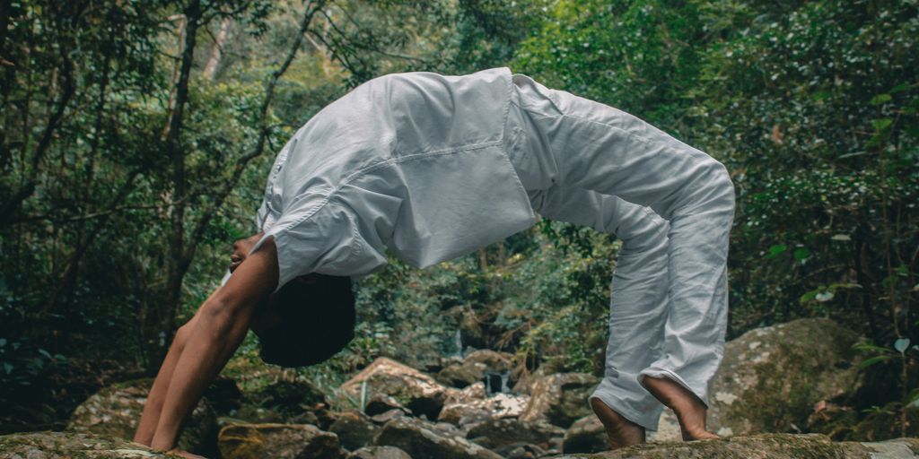 man in white long sleeve shirt and white pants standing on rocky ground