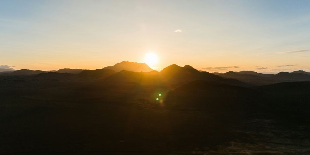 the sun is setting over a mountain range